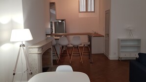 Un espacio habitable compacto con kitchenette, comedor y zona de estar.