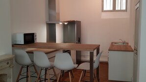 Una cocina compacta con microondas, dos armarios, un lavamanos y un comedor con cuatro sillas.