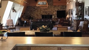 Une cuisine avec des meubles en bois, une cheminée en pierre et un coin repas comprenant une table et des chaises.