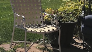 Une terrasse avec une chaise, des plantes en pot et une vue sur un lac et des montagnes.
