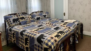 Ein Schlafzimmer mit einem Bett, das mit einer gemusterten Steppdecke bezogen ist, einem Holz-Kopfteil und einer Tür mit einem hellblauen Feld.
