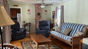 Ein Wohnzimmer mit einer Couch, einem Sessel, einem Holztisch und einem gemusterten Teppich.