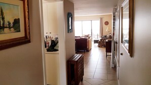 A hallway leading to a living area with a sofa, a table, and a chair. There is a painting on the wall and a clock on the wall. - Relaxing beachfront condo (Fripp Island)