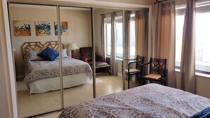 A hotel room with a bed, a chair, a table, and a mirror. - Relaxing beachfront condo (Fripp Island)