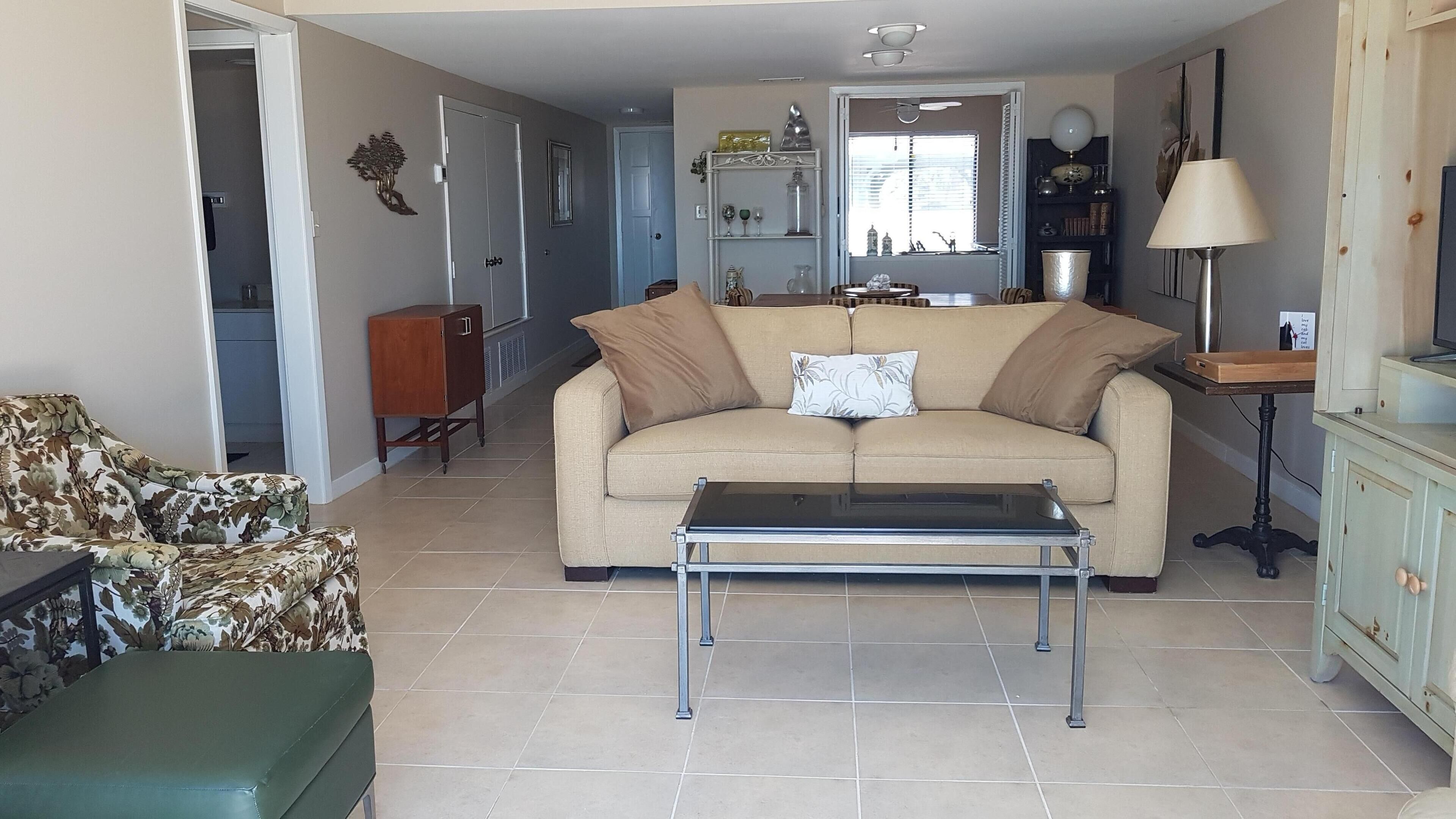 A living room with a beige sofa, a green armchair, a coffee table, and a wooden cabinet.