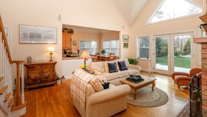 A spacious living room with a high ceiling, a dining area, and a kitchen. - Light and Bright East Hampton Home, Perfect Location! (East Hampton)