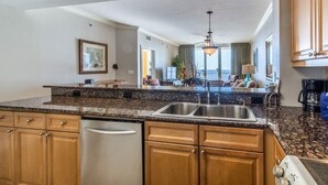 A modern kitchen with granite countertops, stainless steel appliances, and wooden cabinets. - Azure -  Penthouse Level - FREE Beach Service for 4 - Amazing! 3BR 3BA  Sleeps 8 (Fort Walton Beach)