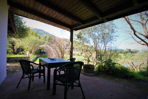 Relax on the patio surrounded by lush gardens and a serene landscape view.