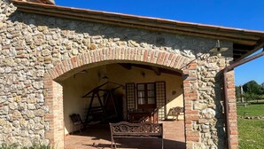 A stone building with a brick archway leading to an outdoor seating area with a metal bench and a table. - Farmhouse Podere dell'Olmo in Umbria - Holiday Home (Ida's House) (Amelia)