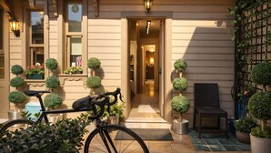Un espacio exterior bien cuidado con una bicicleta, plantas en macetas y una silla.