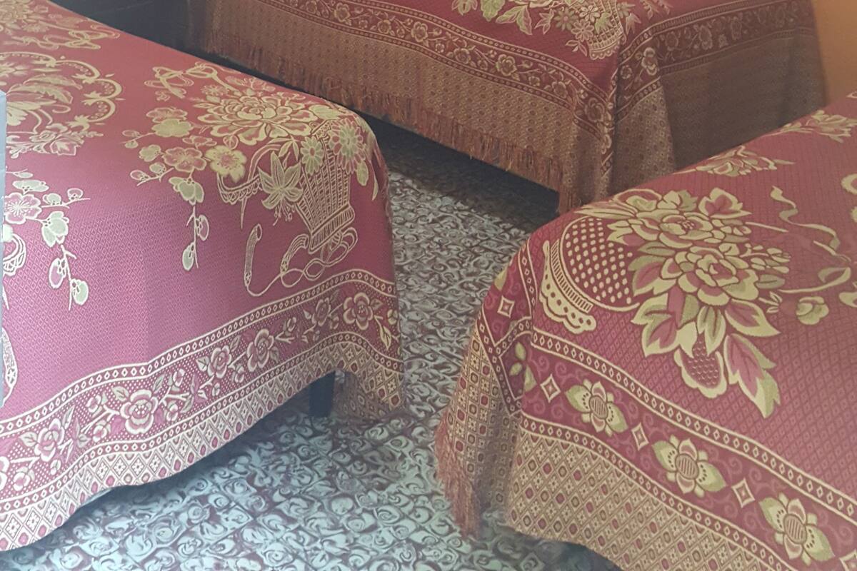 A room with two beds, each with a patterned bedspread, a small table, and a ceiling light fixture.