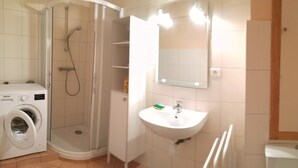 Un bagno dotato di lavatrice, lavandino, specchio e doccia.