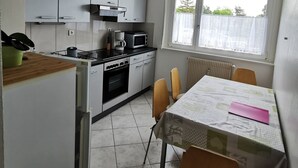 Una cucina funzionale con zona pranzo, che include un tavolo con sedie, una finestra con vista e un termosifone.