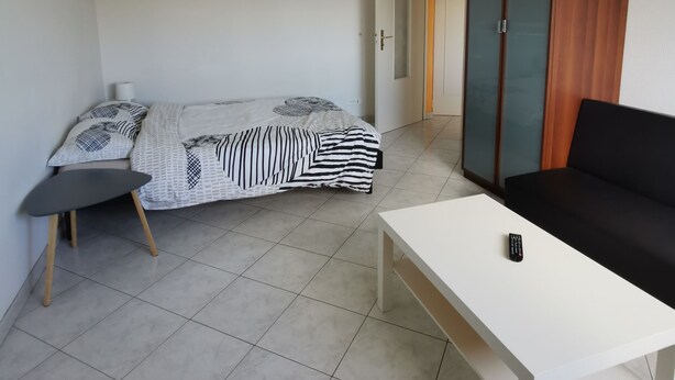 Una camera da letto con un letto, un tavolo bianco, un divano nero e un armadio.
