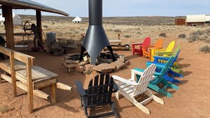 A rustic outdoor setting with a metal chimney, colorful Adirondack chairs, and a wooden table. - Luxury Glamping!  Near Horseshoe, Antelope Canyon, Lake Powell, Grand Canyon.' (Page)