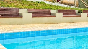 Una piscina con bordi piastrellati e un solarium in pietra.