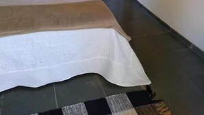 Una camera da letto con un letto grande, una pianta in vaso e una porta che conduce al bagno.