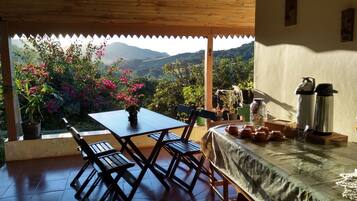 Mesa de madeira com cadeiras e vista para montanhas.