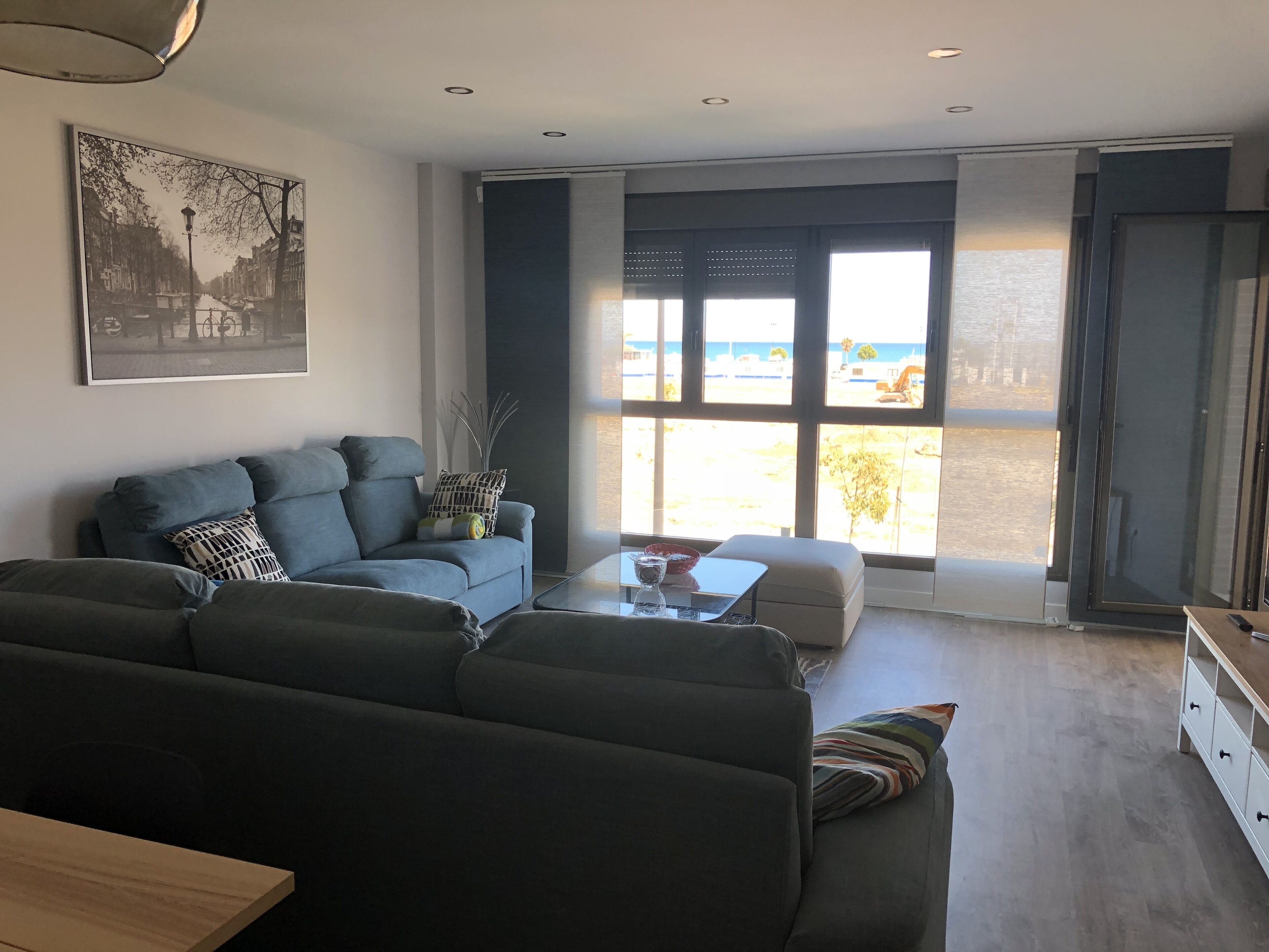 Un salon moderne avec un canapé, une table basse et une vue sur la mer grâce à de grandes fenêtres.