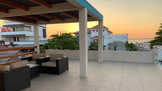 A covered outdoor seating area with wicker furniture and a view of the sunset. - Mid Town Loaf rental (San Pedro)