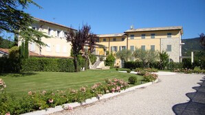 A two-story building with a stone facade and a tiled roof, surrounded by a well-maintained garden with a gravel driveway. - Prestigious penthouse with large panoramic terrace (Marciaga)