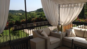 A balcony with wicker furniture, a table, and curtains. - Prestigious penthouse with large panoramic terrace (Marciaga)