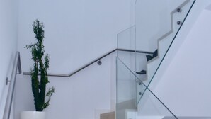 A modern staircase with glass railings and a potted plant. - Amora Villa-Vilamoura (vilamoura)