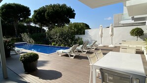 A modern outdoor patio with a pool, lounge chairs, and a table. - Amora Villa-Vilamoura (vilamoura)
