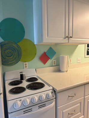 A kitchen with a white stove, cabinets, and a wall-mounted outlet. - 1.3 miles to beach & conveniently located to  fishing,restaurants & shopping! (Corpus Christi)