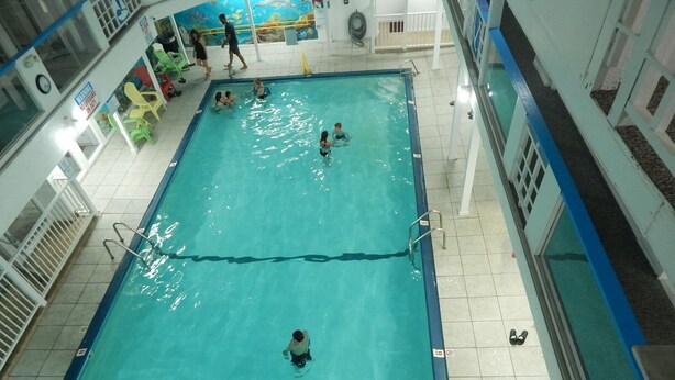 Une piscine intérieure à l’eau claire, dotée d’un plongeoir et d’un poste de surveillance pour le sauveteur.