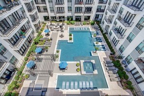 Un hotel moderno con area piscina centrale, numerosi balconi e posti a sedere all'aperto.