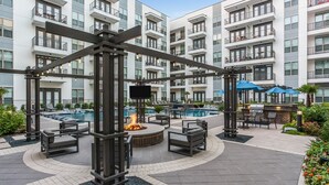 Ein moderner Poolbereich im Freien mit Liegestühlen, einer Feuerstelle und einer Bar.