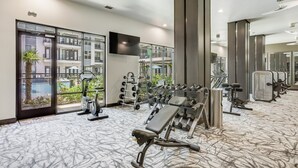 Ein modernes Fitnessstudio im Hotel mit Trainingsgeräten, großen Fenstern und Blick auf das äußere Gebäude.