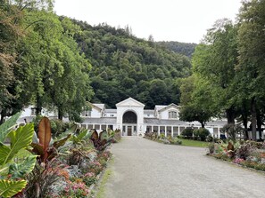 A building with a central entrance, surrounded by a gravel path and lush greenery. - T2 apartment of 28 m2 (Bagnères-de-Luchon)
