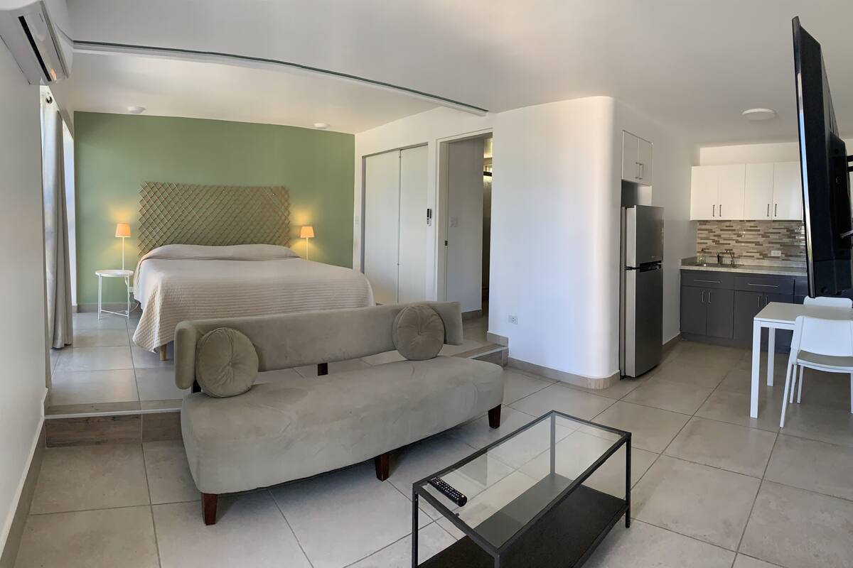 A modern hotel room with a bed, sofa, and a glass coffee table.