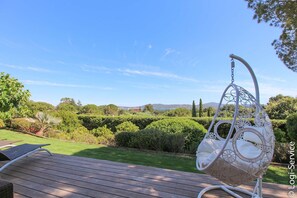 Una terraza de madera con una silla colgante y una mesa.