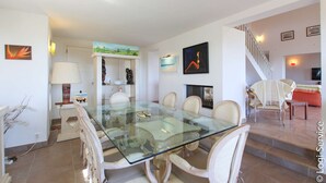 A dining area with a glass table and chairs, a staircase, and artwork on the walls. - Near the beach, villa 8 persons with a pool and air-conditioned bedrooms. (GRIMAUD)