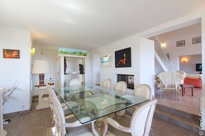 A dining area with a glass table and chairs, a staircase, and artwork on the walls. - Near the beach, villa 8 persons with a pool and air-conditioned bedrooms. (GRIMAUD)