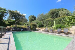 A clear swimming pool with lounge chairs and umbrellas, surrounded by greenery and trees. - Near the beach, villa 8 persons with a pool and air-conditioned bedrooms. (GRIMAUD)