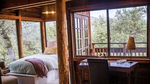 A bedroom with a large window, a wooden desk, and a chair. - Gorgeous Secluded Treehouse with Spectacular Views (Carmel Valley)