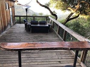 A wooden deck with outdoor furniture, a railing, and a view of a mountainous landscape. - Gorgeous Secluded Treehouse with Spectacular Views (Carmel Valley)
