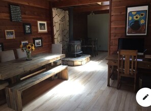 A wooden interior with a stone wall, a fireplace, and a dining area with benches and a table. - Gorgeous Secluded Treehouse with Spectacular Views (Carmel Valley)