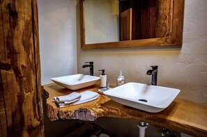 A bathroom with two white vessel sinks, wooden vanity, and a mirror above the sinks. - Gorgeous Secluded Treehouse with Spectacular Views (Carmel Valley)