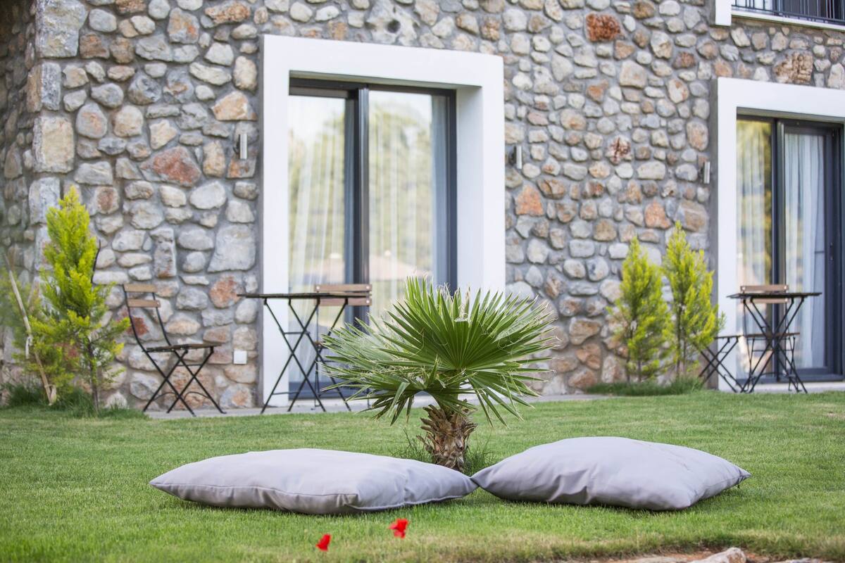 A stone building with a well-maintained lawn, two small tables, and a palm tree.