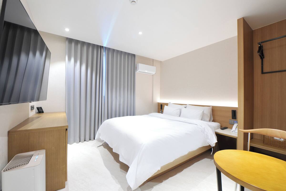 Una habitación de hotel moderna con una cama grande, un escritorio, una silla y un televisor de pantalla plana.