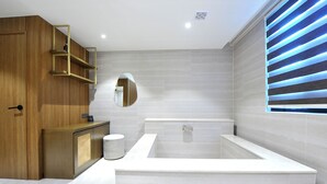 Un baño moderno con una bañera grande, muebles de madera y un espejo.