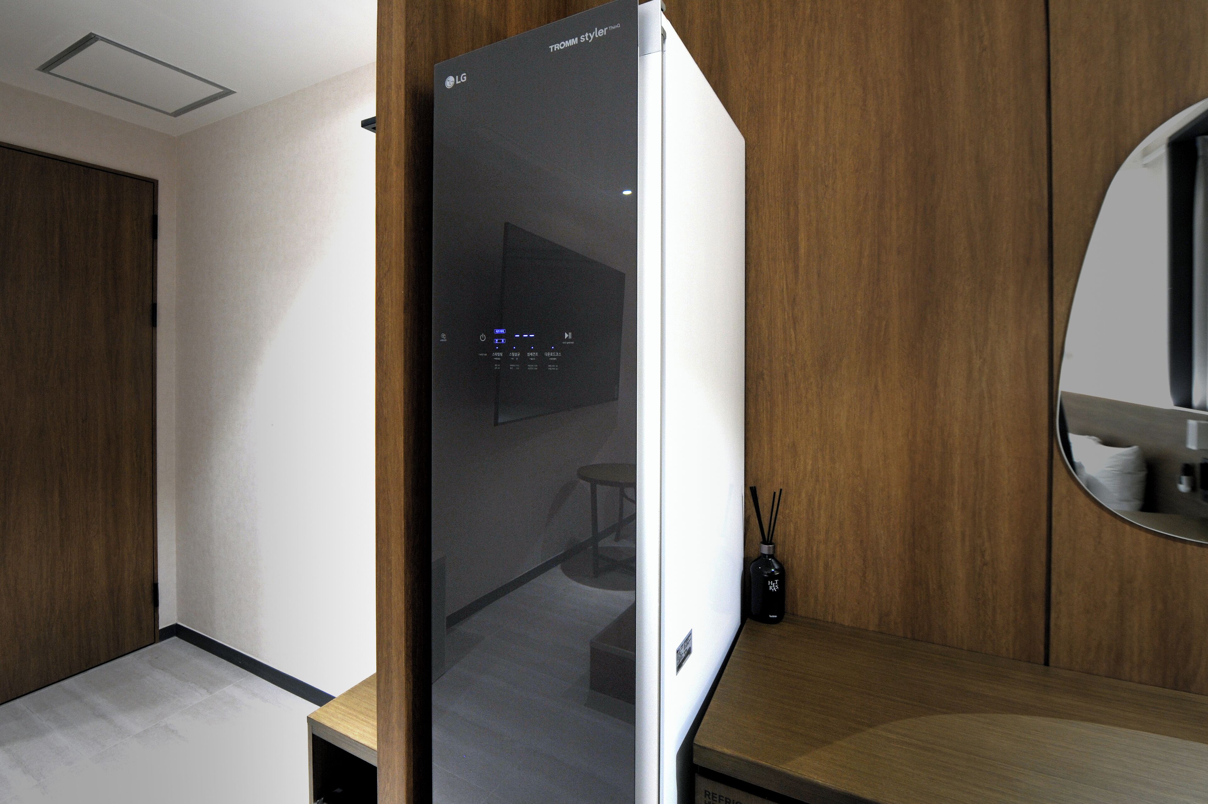 Eine moderne Küche mit einem eingebauten LG-Kühlschrank, Holzschränken und einem runden Spiegel über der Arbeitsfläche.