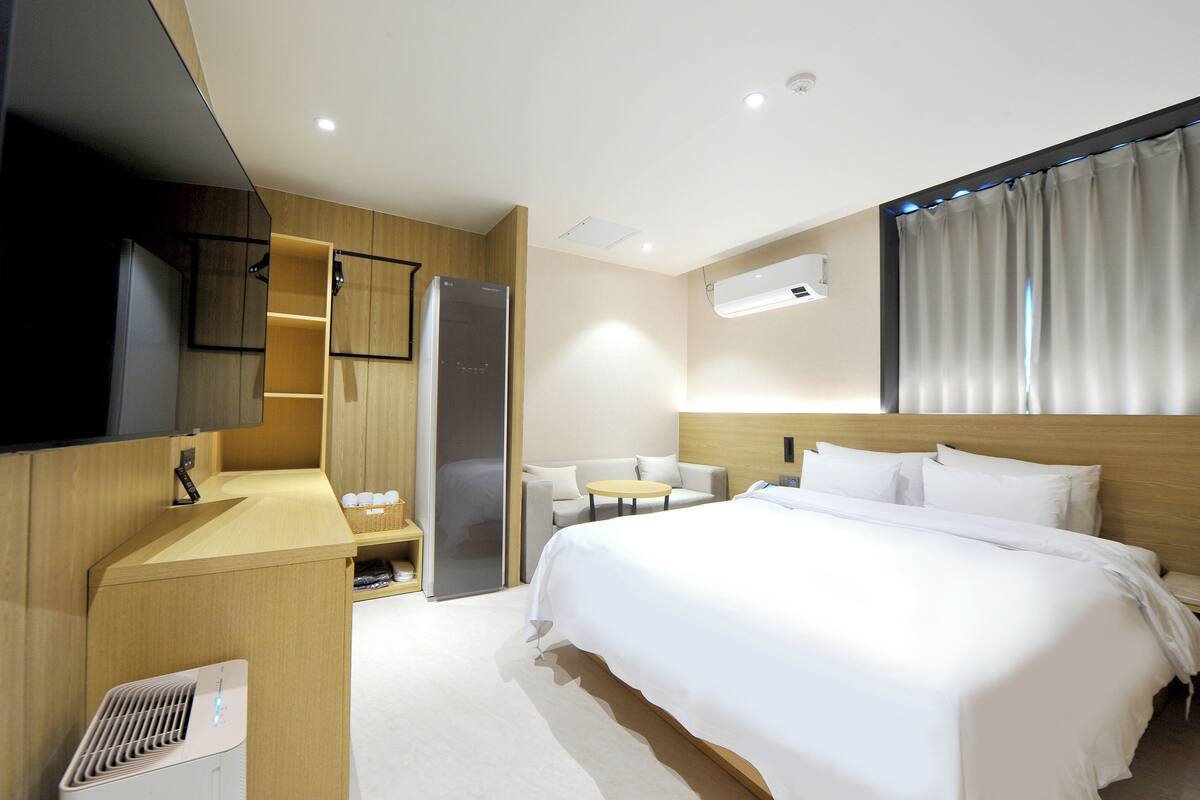 Una habitación de hotel con cama, escritorio, silla, televisión y armario.