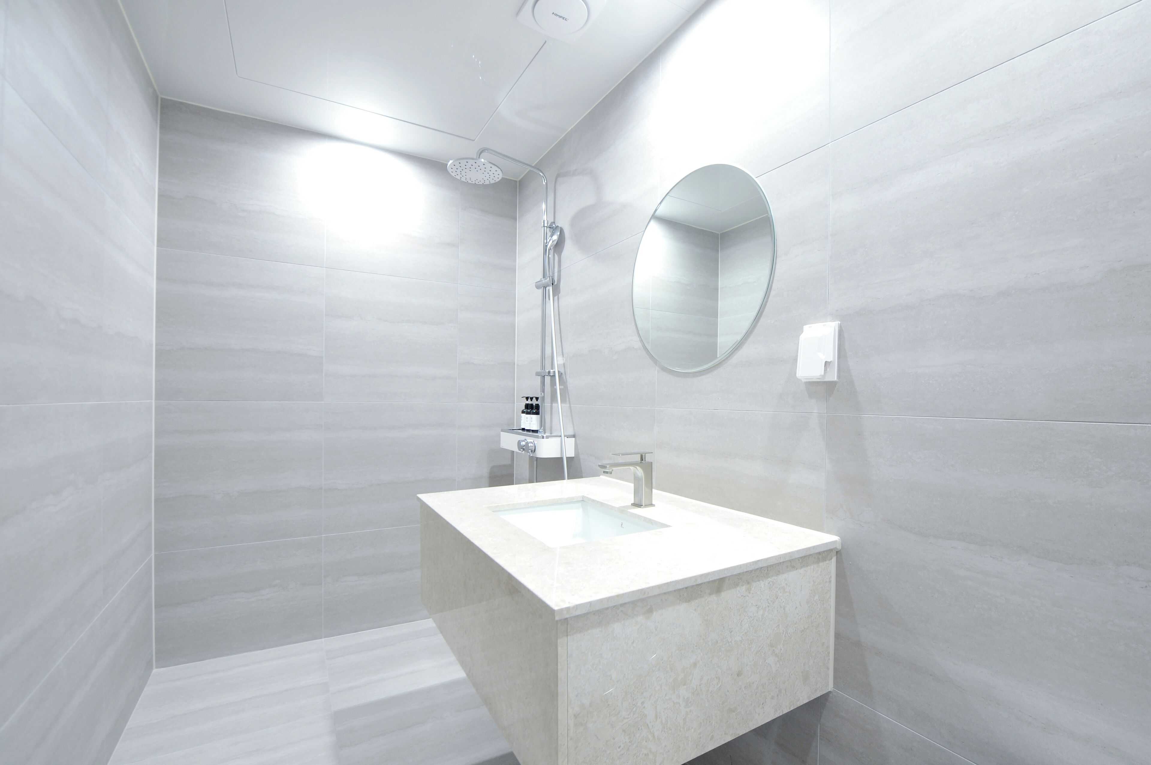 Un baño moderno con un espejo grande, una ducha y un lavabo.