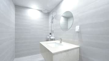 Un baño moderno con un espejo grande, una ducha y un lavabo.